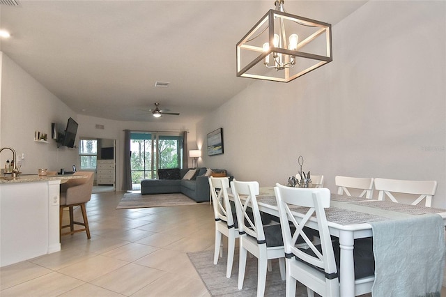 tiled dining area featuring sink and ceiling fan with notable chandelier