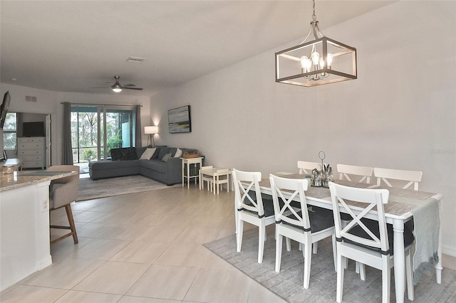 tiled dining area with ceiling fan with notable chandelier