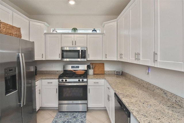 kitchen featuring white cabinets, light stone counters, light tile patterned floors, and appliances with stainless steel finishes