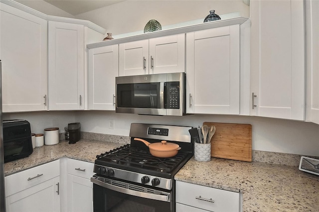 kitchen featuring white cabinets, stainless steel appliances, and light stone countertops