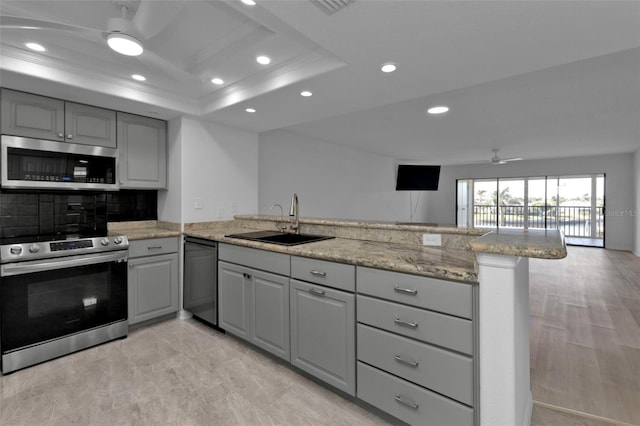 kitchen with gray cabinetry, sink, stainless steel appliances, kitchen peninsula, and a tray ceiling