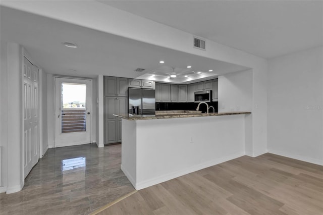 kitchen featuring gray cabinetry, light wood-type flooring, kitchen peninsula, and stainless steel appliances