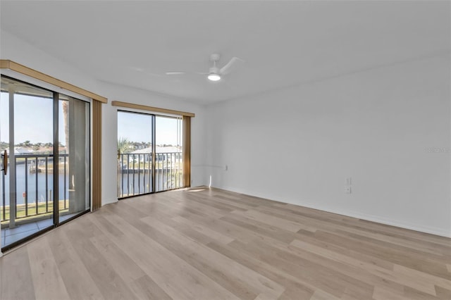 unfurnished room featuring ceiling fan, a water view, and light hardwood / wood-style flooring