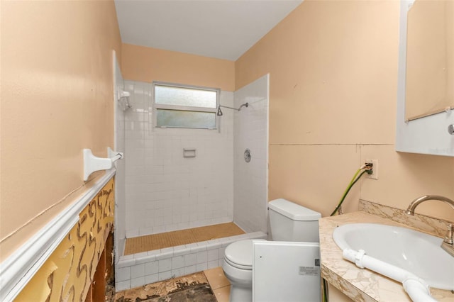 bathroom with a tile shower, tile patterned flooring, vanity, and toilet