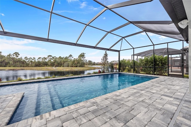 view of pool featuring glass enclosure, a water view, and a patio