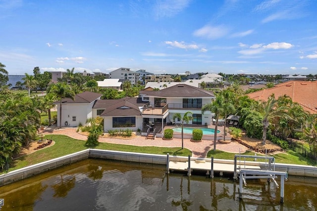 back of property with a balcony, a water view, and a patio