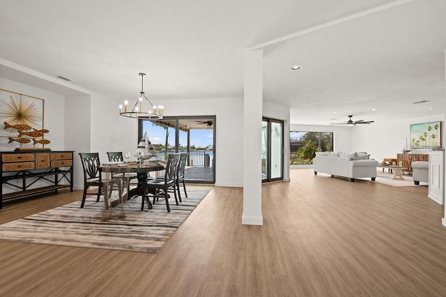 dining space featuring ceiling fan with notable chandelier and wood-type flooring