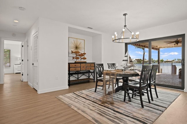 dining area featuring wood-type flooring and ceiling fan with notable chandelier