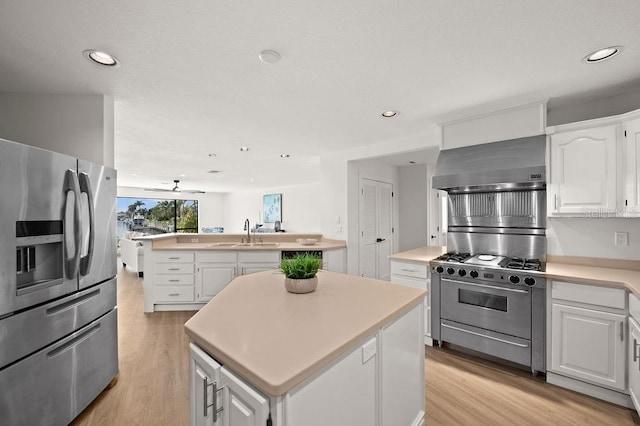 kitchen with sink, white cabinetry, wall chimney range hood, an island with sink, and stainless steel appliances