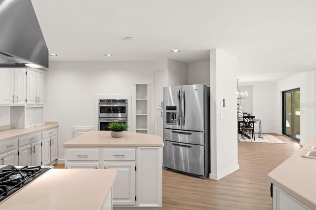 kitchen featuring range hood, white cabinetry, a center island, and stainless steel appliances