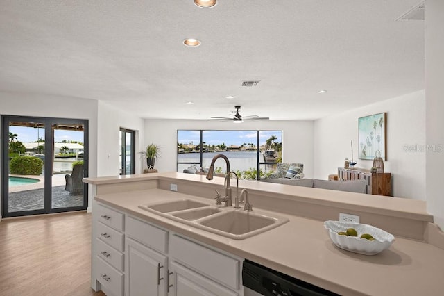 kitchen featuring sink, a wealth of natural light, white cabinets, and light wood-type flooring