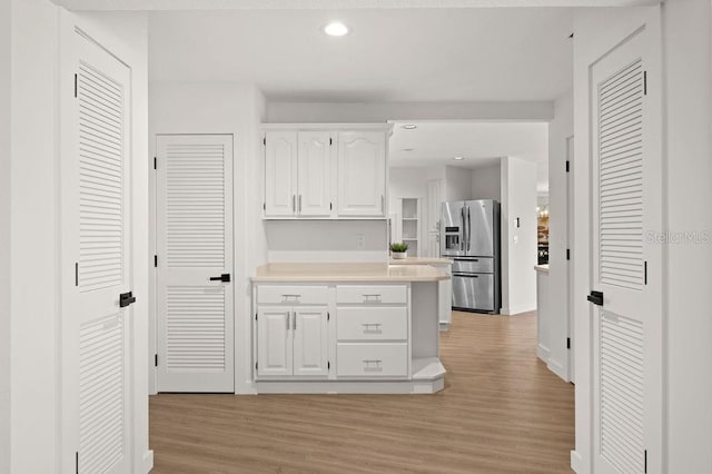 kitchen featuring white cabinets, light wood-type flooring, and stainless steel refrigerator with ice dispenser