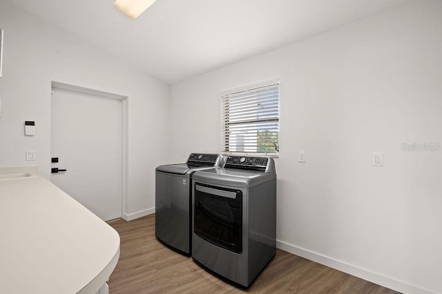 laundry area with separate washer and dryer and hardwood / wood-style flooring