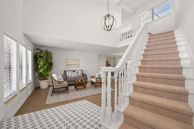 foyer entrance featuring a chandelier, light hardwood / wood-style flooring, and a towering ceiling