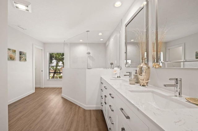 bathroom featuring hardwood / wood-style flooring, a shower, and vanity