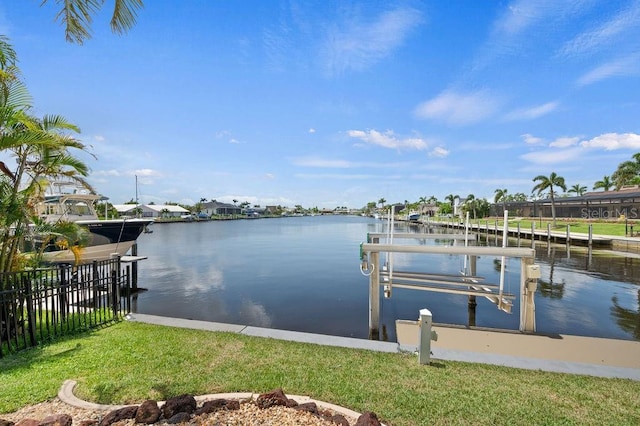 view of dock with a lawn and a water view