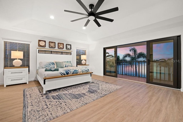 bedroom featuring ceiling fan, light hardwood / wood-style floors, a raised ceiling, and access to outside