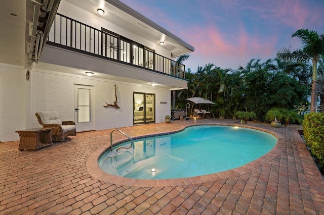 pool at dusk with a patio