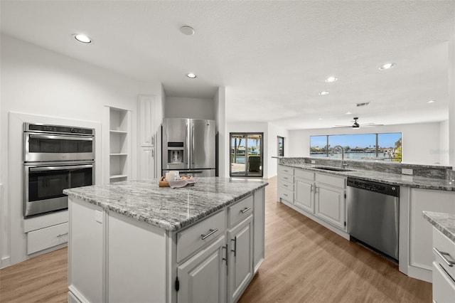 kitchen with light wood-style flooring, a kitchen island, stainless steel appliances, and a sink