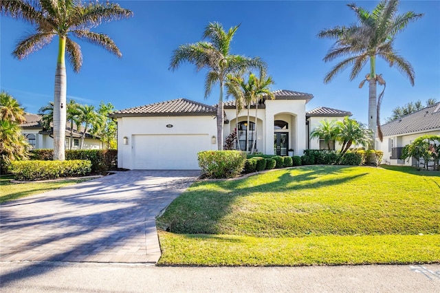 mediterranean / spanish home with a garage and a front lawn