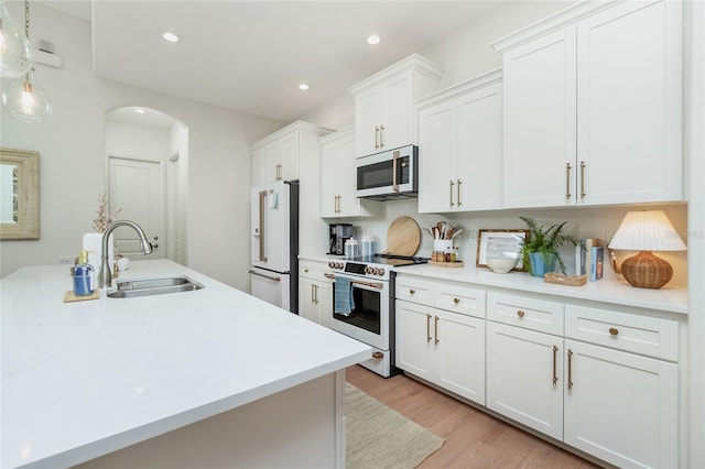 kitchen featuring high quality appliances, sink, light hardwood / wood-style flooring, and white cabinetry