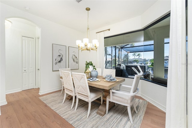 dining space with light hardwood / wood-style floors and a chandelier