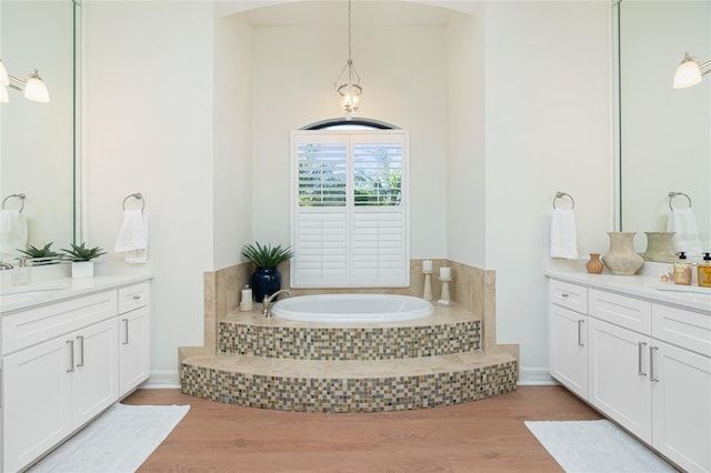 bathroom with tiled tub, vanity, and hardwood / wood-style flooring