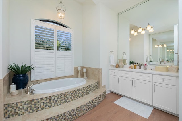 bathroom featuring tiled bath, vanity, and hardwood / wood-style flooring