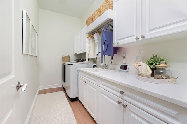 laundry area featuring washer and dryer, light wood-type flooring, and cabinets