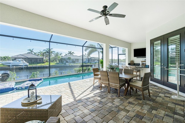 interior space with an outdoor kitchen, french doors, glass enclosure, ceiling fan, and a water view