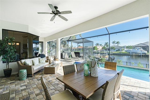 sunroom / solarium with ceiling fan and a water view