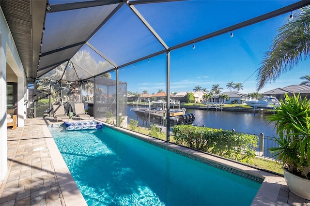 view of swimming pool with a lanai, a patio area, and a water view