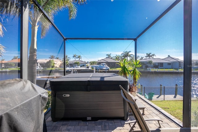 view of patio / terrace with a hot tub, a water view, area for grilling, and glass enclosure