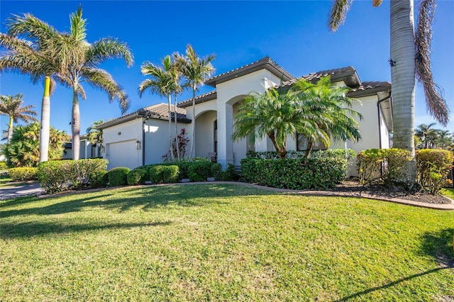 mediterranean / spanish house featuring a front yard and a garage