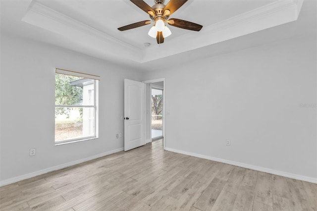 spare room featuring ceiling fan, light hardwood / wood-style flooring, ornamental molding, and a tray ceiling