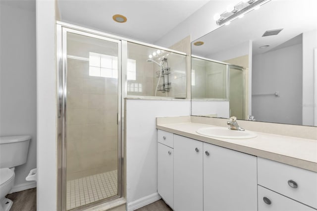 bathroom featuring toilet, vanity, a shower with shower door, and hardwood / wood-style floors