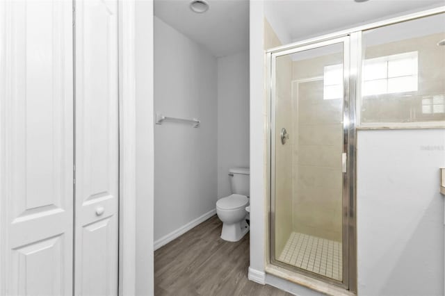 bathroom featuring a shower with door, hardwood / wood-style flooring, and toilet