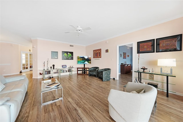 living room featuring crown molding, a fireplace, ceiling fan, and light hardwood / wood-style flooring