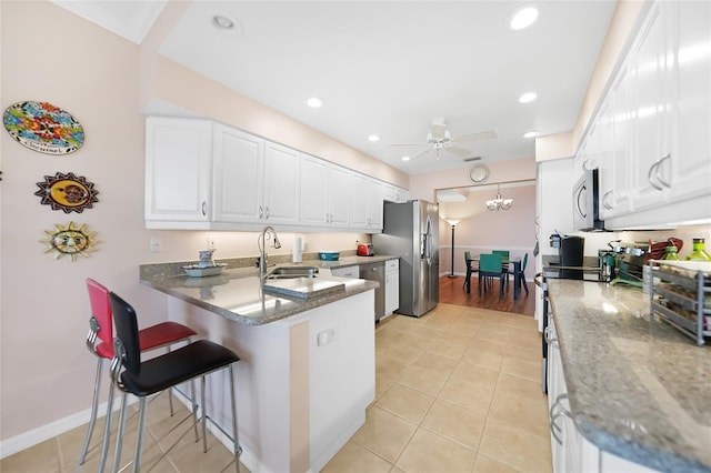 kitchen featuring sink, white cabinetry, dark stone countertops, and kitchen peninsula