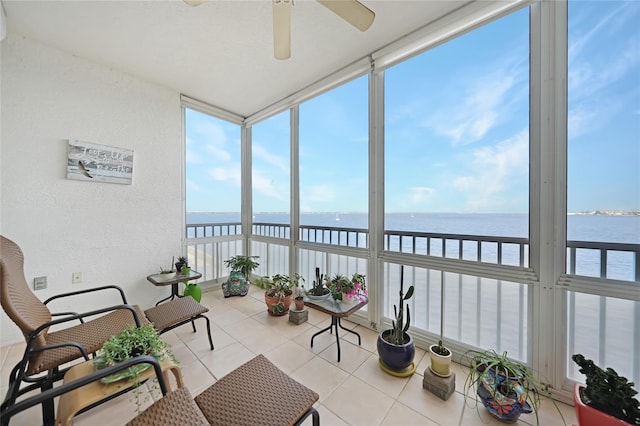 sunroom featuring ceiling fan, a healthy amount of sunlight, and a water view