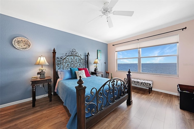 bedroom featuring hardwood / wood-style floors, ceiling fan, and a water view