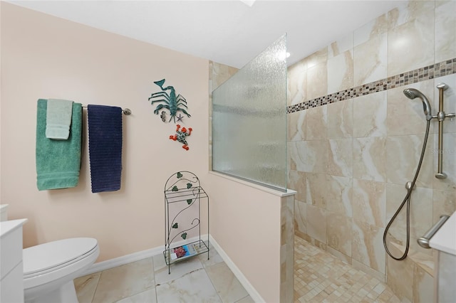 bathroom featuring tile patterned flooring, a tile shower, vanity, and toilet