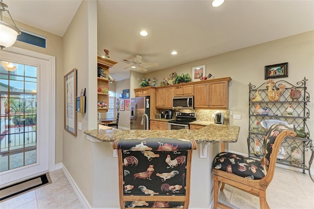 kitchen featuring ceiling fan, decorative backsplash, kitchen peninsula, a breakfast bar area, and stainless steel appliances