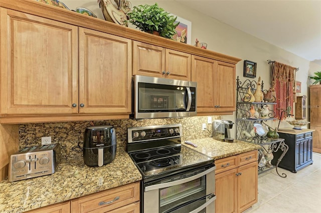 kitchen featuring backsplash, appliances with stainless steel finishes, light tile patterned flooring, and light stone counters