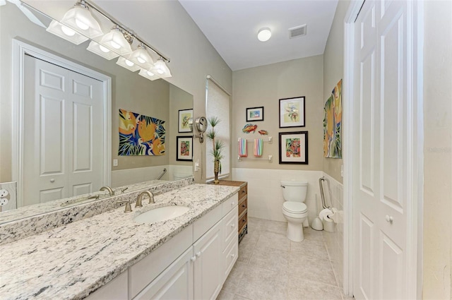 bathroom featuring tile patterned flooring, vanity, tile walls, and toilet