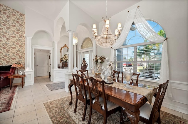 dining room featuring high vaulted ceiling, an inviting chandelier, light tile patterned floors, and ornate columns