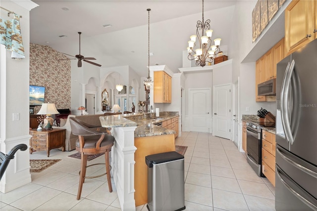 kitchen with kitchen peninsula, decorative light fixtures, stainless steel appliances, ceiling fan with notable chandelier, and a kitchen breakfast bar