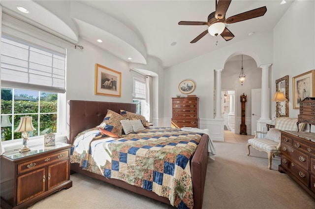 bedroom featuring ensuite bath, ceiling fan, light carpet, and ornate columns