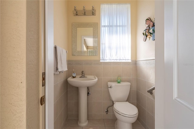 bathroom with tile walls, toilet, tile patterned floors, and sink