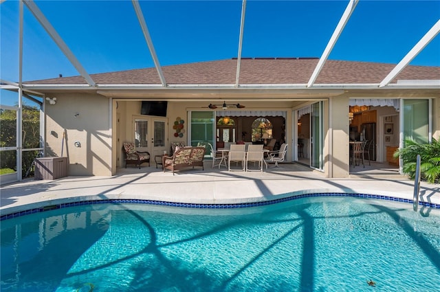 view of swimming pool featuring french doors, a patio area, ceiling fan, and glass enclosure